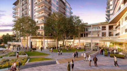 A ground level view of the exterior of a Raleigh wellness community. Residents and visitors enjoy retail, dining, and parks in the foreground of luxury apartments and office space.