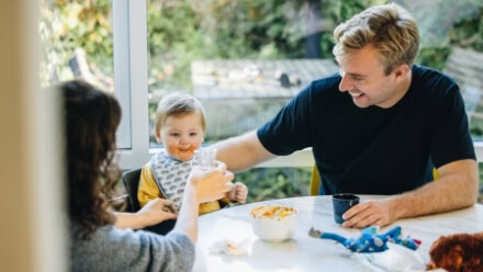 A young family with a baby enjoys breakfast in the kitchen of their luxury Raleigh apartment at The Exhange, where multifamily homes prioritize community health and wellness