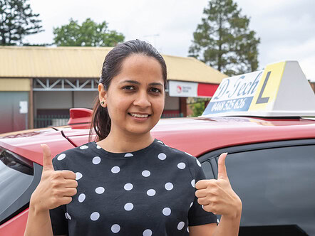Happy driver training student giving double thumbs-up directly in front of the Richmond RMS office building