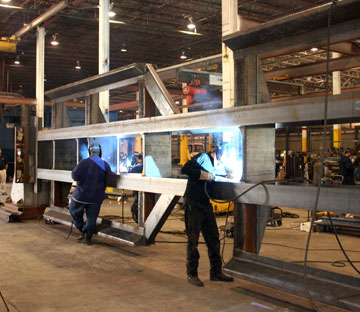 Image of two welders in a trailer manufacturing plant welding on a long run