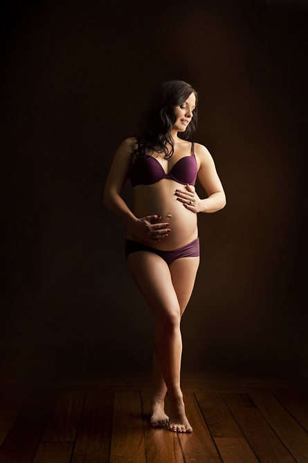 Kvinne som poserer for gravidfotografering, gravid i undertøy, portrett av mor i studio.