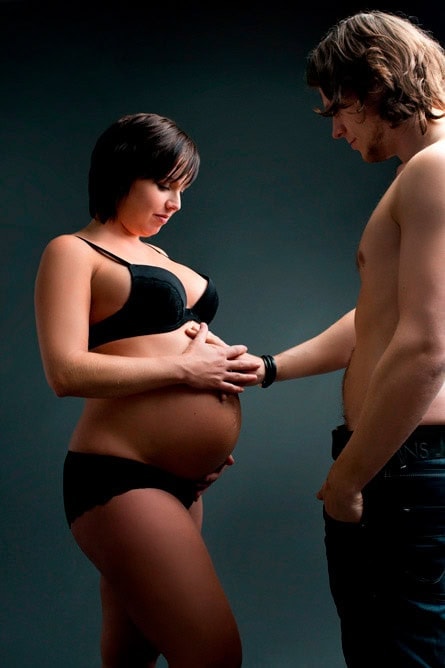 Bilde av en gravid kvinne og hennes partner som får profesjonell gravidfotoshoot, fokus på kjærlighet og forventning. Perfekt for gravidefotografering og minneverdige øyeblikk.