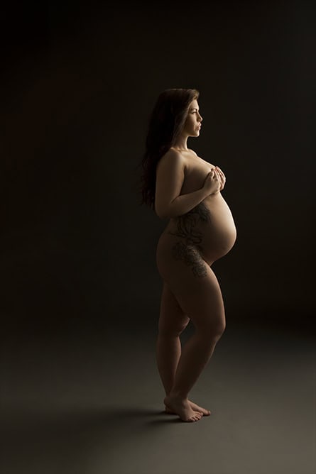 Eksklusiv gravidfotografering av gravid kvinne med mage i fokus, kunstnerisk bilder for å feire morskapet. Professionell gravidfoto for å fange det vakre øyeblikket.