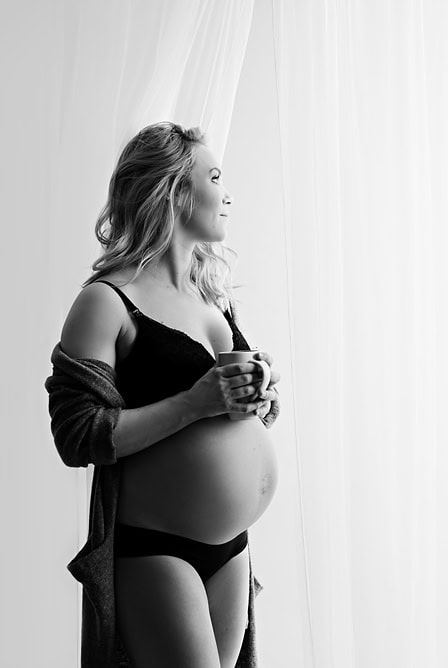 Høy kvalitet gravidfoto av gravid kvinne som holder kopp, natural lys og myk bakgrunn, perfekt for minner og familiealbum.