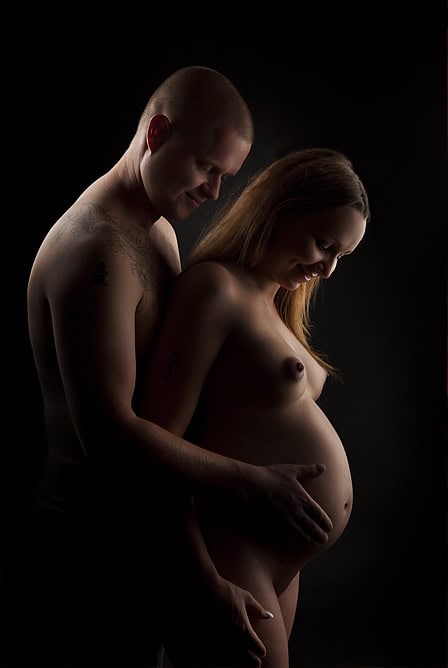 Elegant gravidfoto av et vakkert, kommende mor og far med fokus på magen, tatt i studio for å fange magiens øyeblikk før fødsel. Perfekt for gravide fotosesjoner og minner for livet.