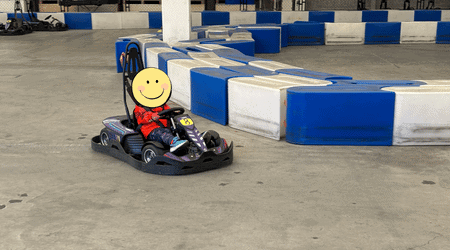 屋内コースのカーブを曲がる子供用のEVカート。トムス社製の本格的なマシンを運転している様子