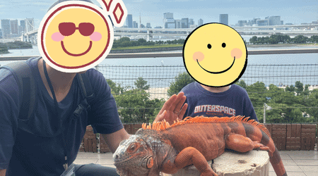 お台場の景色を背景に、アニミルの看板動物である巨大イグアナと一緒に記念撮影をする親子