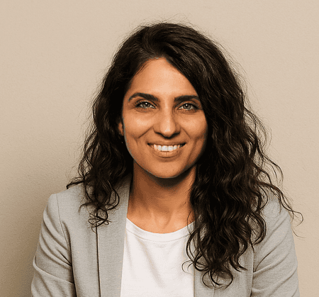Headshot of Ghazaleh, with dark curly hair, minimalist attire, and a smile.