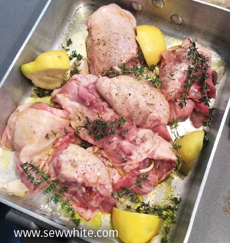 Chicken thighs with lemon in an oven tray with fresh thyme