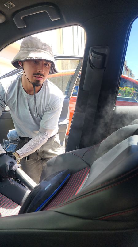 Guillermo steam-cleaning a car seat