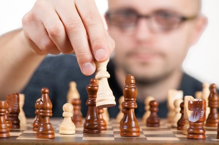 Man playing chess, focusing on strategic move at Quantilia.
