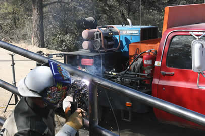 A welder using a Dura-Flux gun to weld a metal guardrail