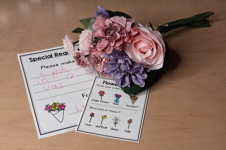Photo of plastic flowers and orders slips for a pretend flower shop.