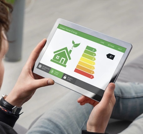 Tablette affichant l'interface domotique Smart Home Energy avec un graphique de classe énergétique A+ pour la gestion d'énergie qui permet le suivi des consommations électriques et conformité RE2020 par un fabricant domotique français