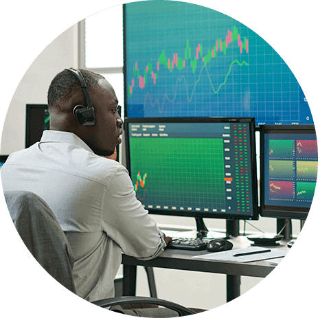 Financial analyst monitoring security-level data on multiple screens.