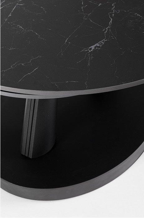 Close-up of a black marble round table top with a silver edge and dark pedestal leg.