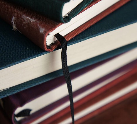 hero-img-02 A detailed view of a stack of colorful hardcover books with visible bookmarks.