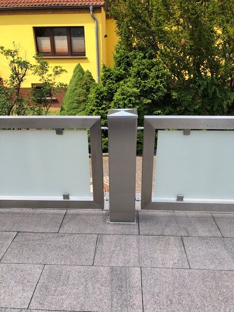 Modernes Edelstahlgeländer mit satinierten Glasfüllungen von Stahl- und Metallbau Drost, auf einer gefliesten Terrasse.