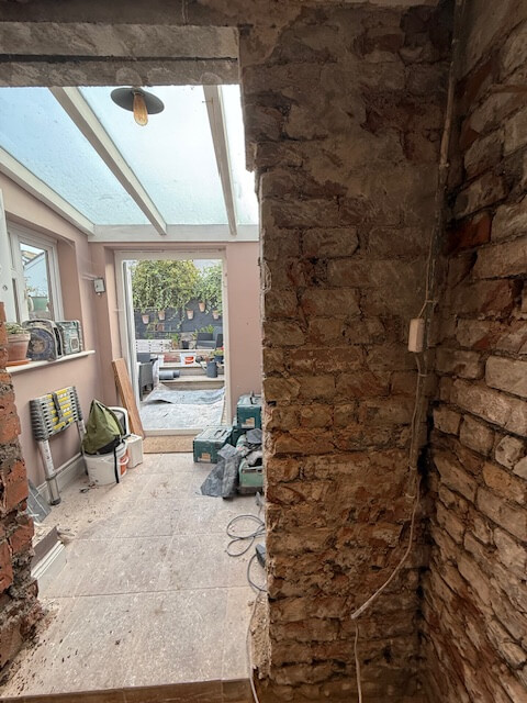 Bare brick wall exposed during damp proofing treatment in a Bristol home