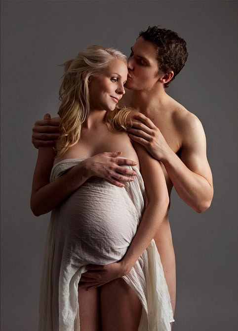 Elegant gravidfoto av et par som omfavner mor med gravid mage, fokus på kjærlighet og intimitet. Perfekt for gravide fotografia og å fange det vakre øyeblikket før fødselen.