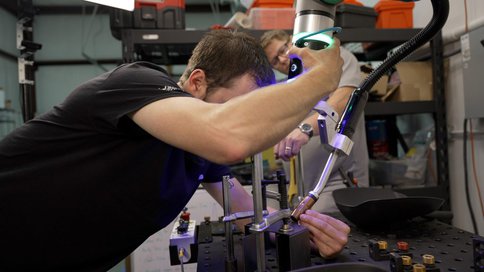 Side view of operator moving a cobot MIG gun in place prior to welding