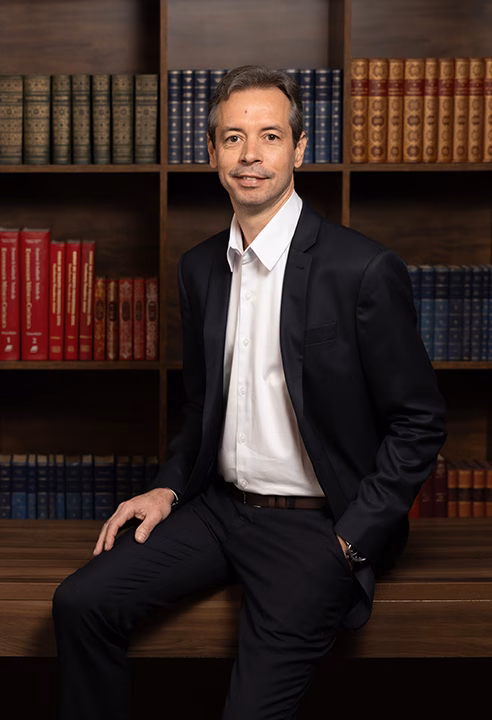 Foto profissional de médico de terno em frente a uma estante de livros, feita no estúdio em BH