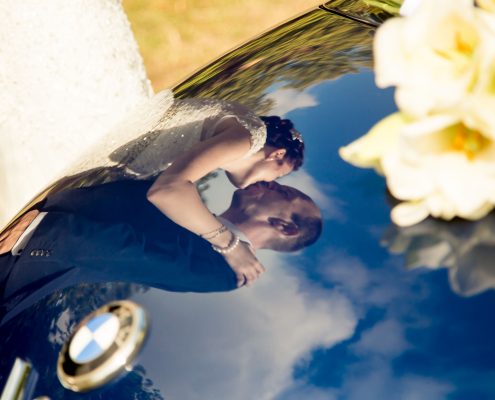 Brautpaar spiegelt sich im Kofferraum des HochzeitsAutos