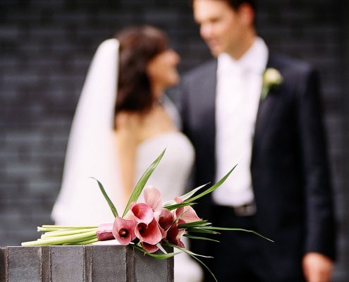 Brautstrauß mit Brautpaar unscharf im Hintergrund