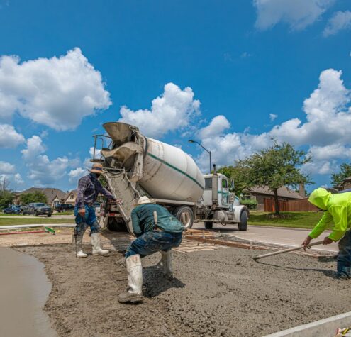 Concrete workers pouring a new driveway in Fort Worth, TX under a bright blue sky, for Kitchener home ROI guide.