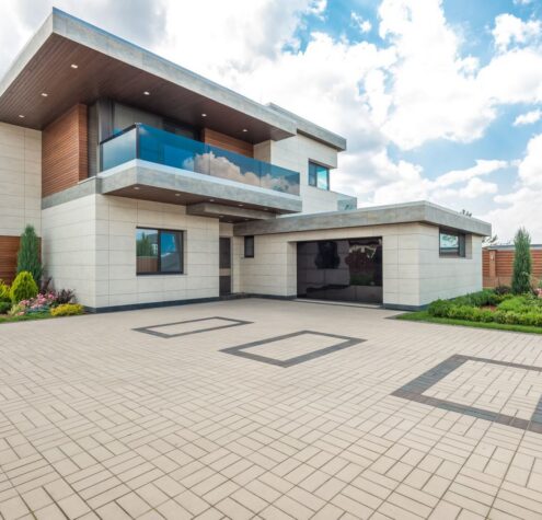 Modern home exterior with lush landscaping and wide concrete driveway, ideal for a 2000 sq ft summer installation in Kit