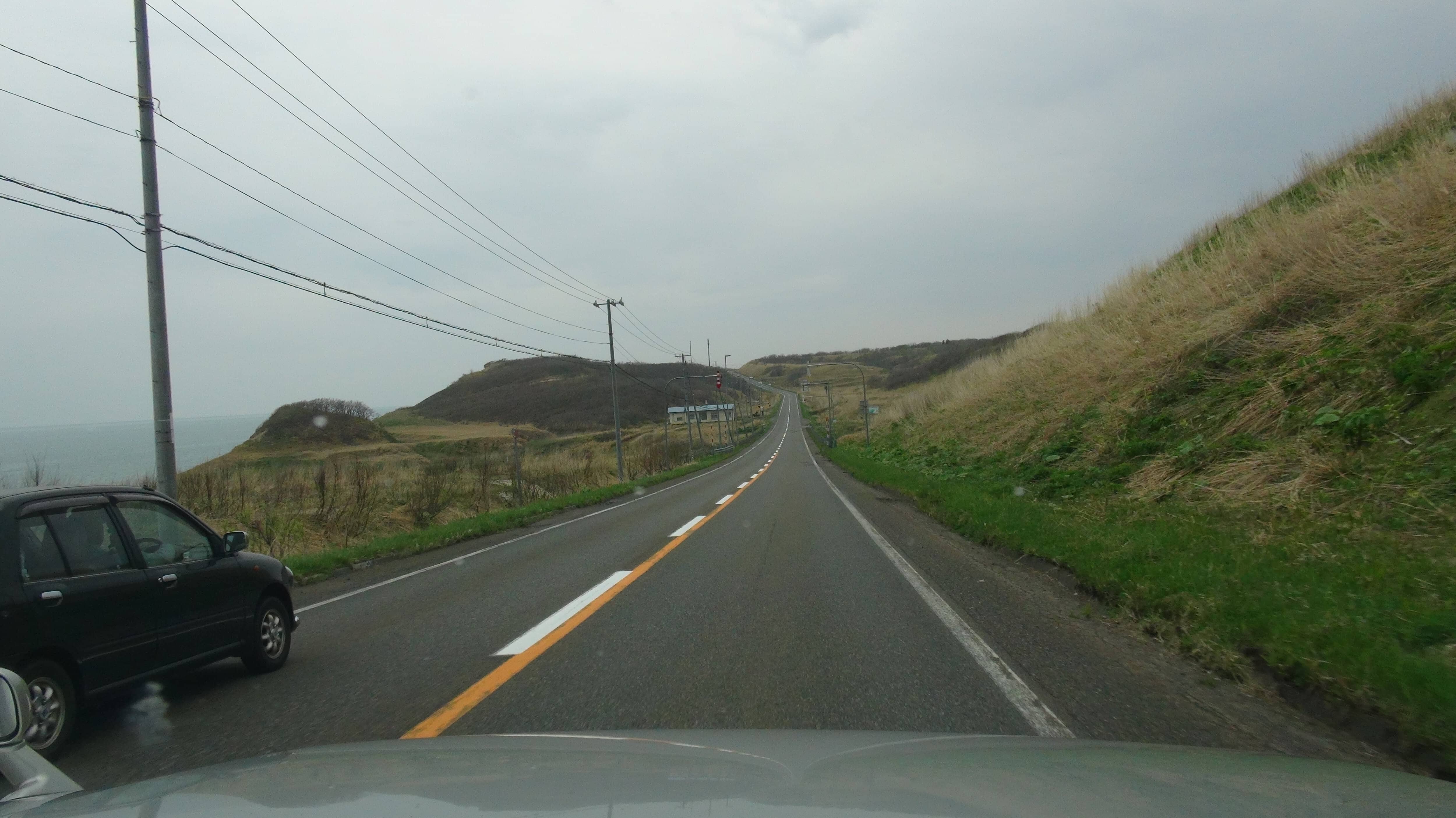 車窓から見た北海道の直線道路(牧草地と海)