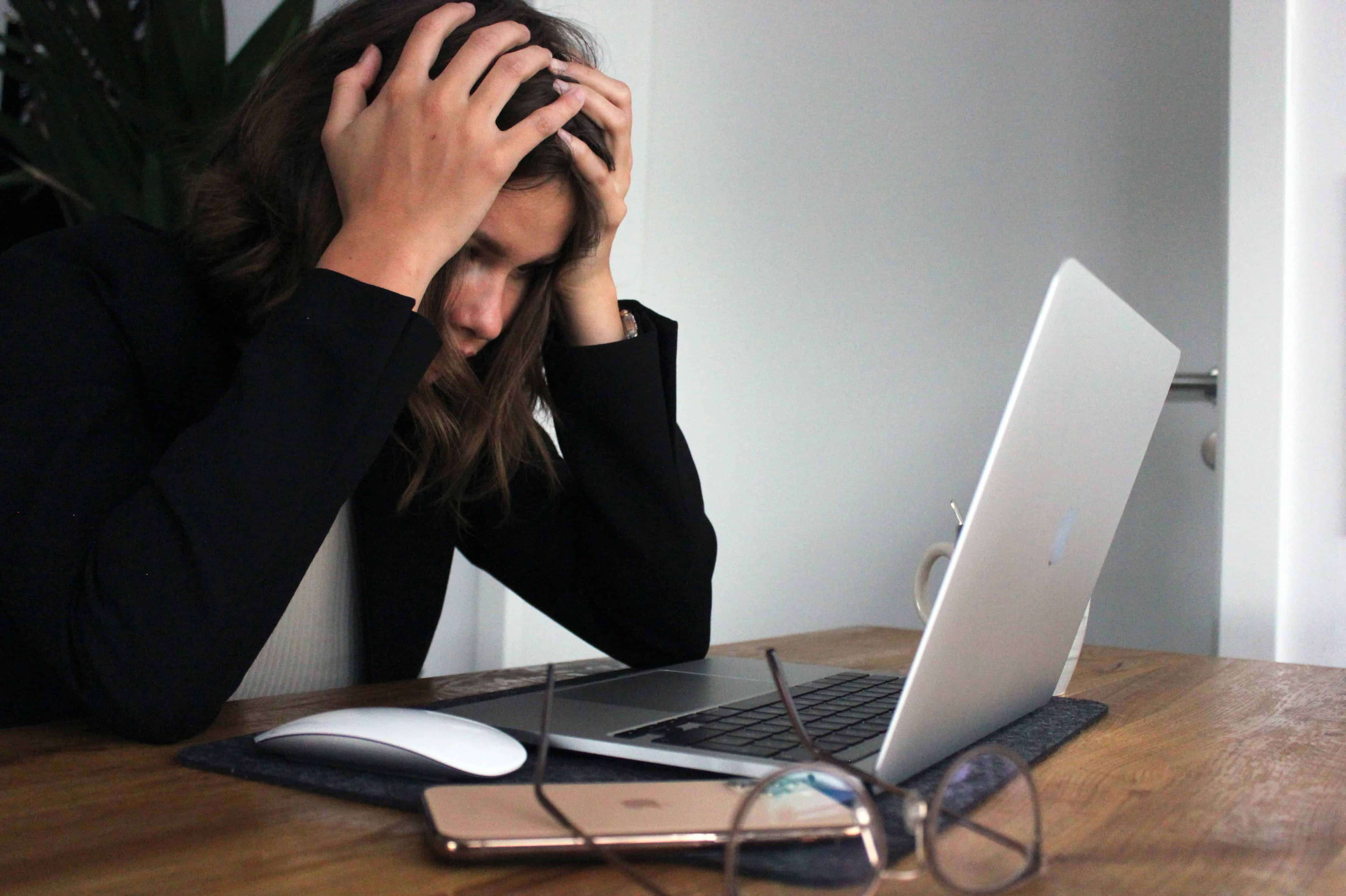 Woman slumped over laptop looking stressed