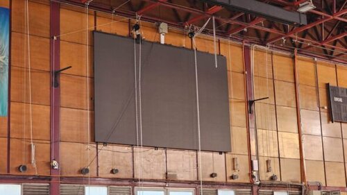 Pantalla LED de gran formato colgada desde estructura superior en el gimnasio del Colegio Salesianos de Alameda, lista para operación audiovisual