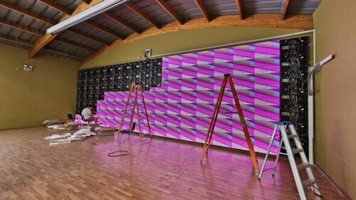 Proceso de instalación de pantalla LED P2.5 en el gimnasio del Colegio Tupahue, con módulos en montaje y pruebas visuales