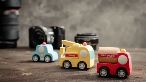 Wooden toy vehicles including police car, crane and fire engine with cameras in the background