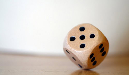 Dice with black dots on a light wooden surface for gaming or decision-making.