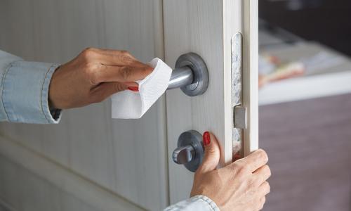 Woman cleaning the door handle with disinfecting wipe Woman cleaning the door handle with disinfecting wipe