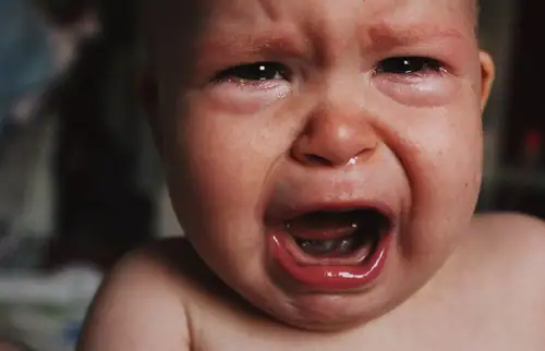 Close-up of tearful baby crying hard with streaming tears
