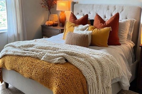 Cozy fall bedroom with a soft tufted queen bed with autumn-colored throw blankets and pillows - seasonal branches in a vase and warm ambient lighting – inspiring fall bedroom decor ideas.