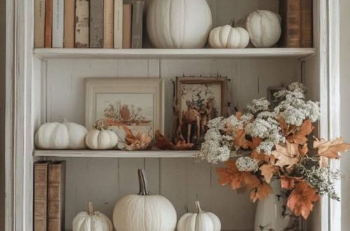 Five‑layer white shelf decorated with pumpkins, stacked books, and autumn leaves — cozy fall shelf ideas showing layered seasonal decor from By Paige Nicole.