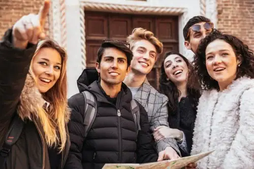 Eine Gruppe fröhlicher, dynamischer Menschen lacht gemeinsam beim Lösen eines Outdoor-Rätsels mit einer geheimnisvollen Tasche von Historix-Tours in Freiburg.