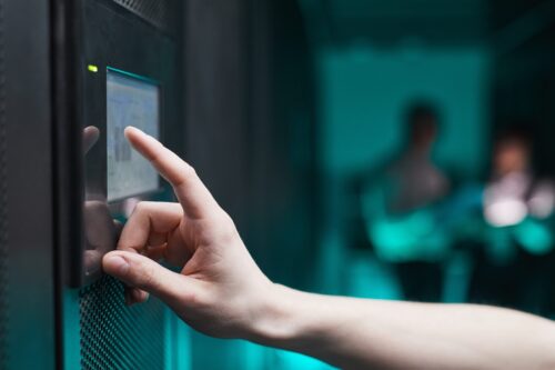 A hand operating a server network device on wall