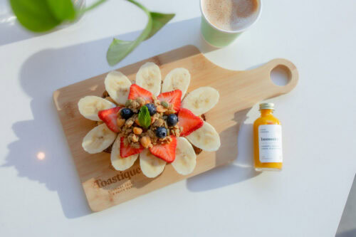 A cutting board with an attractive spread of fresh fruit, announcing the opening of Toastique's first Raleigh cafe