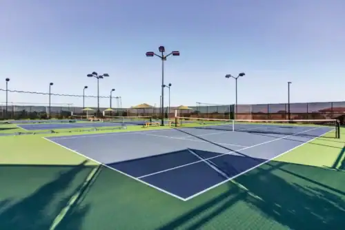 Outdoor professional tennis courts with premium playing surfaces and stadium lighting add to the amenities of a fitness-focused Raleigh apartment