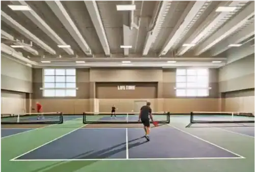 Indoor pickleball courts with players enjoying a match inside a modern sports complex included in a luxury Raleigh apartment's amenities