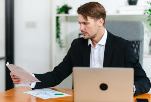 employee looking at IT compliance documents while working on laptop
