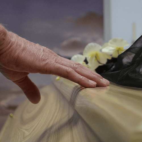 Elderly hand resting on a coffin during a wrongful death funeral in Idaho