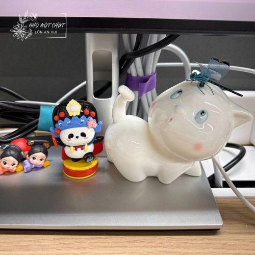 Mèo gốm An Nhiên nằm bên góc làm việc, mẫu tượng gốm mini dễ thương phù hợp decor bàn làm việc, kệ sách và góc học tập.