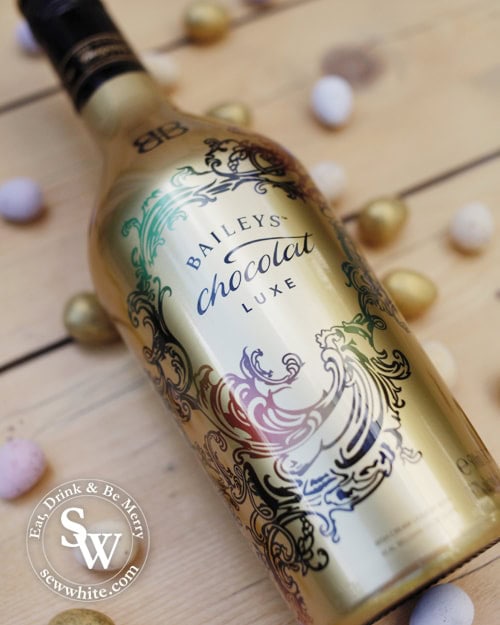 Baileys chocolat luxe in a gold bottle surrounded by mini eggs for the Chocolate Flat White Martini