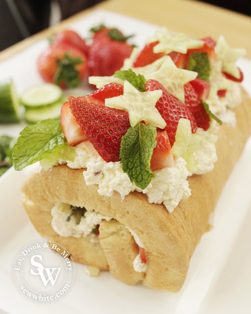 Brightly coloured Pimms Cake roulade perfect for Wimbledon. Topped with fresh strawberries